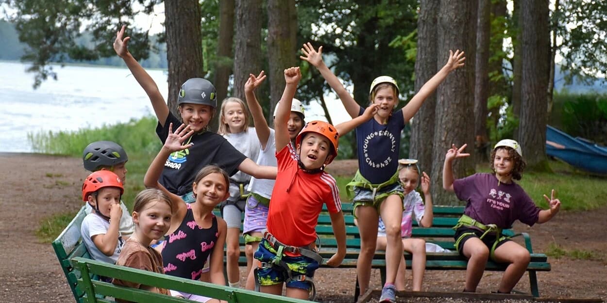 Niños celebrando con los brazos en alto en un campamento de Educate