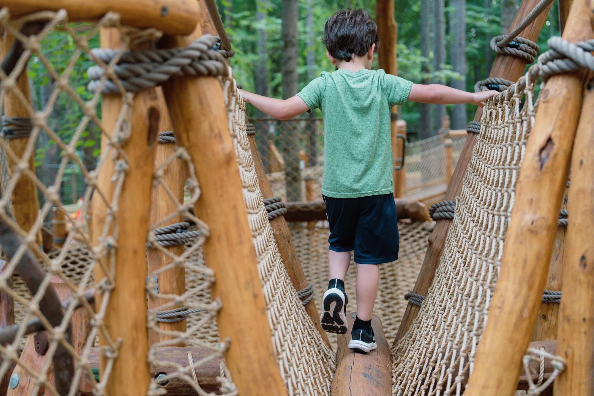 Niño cruzando un puente de cuerdas en el campamento